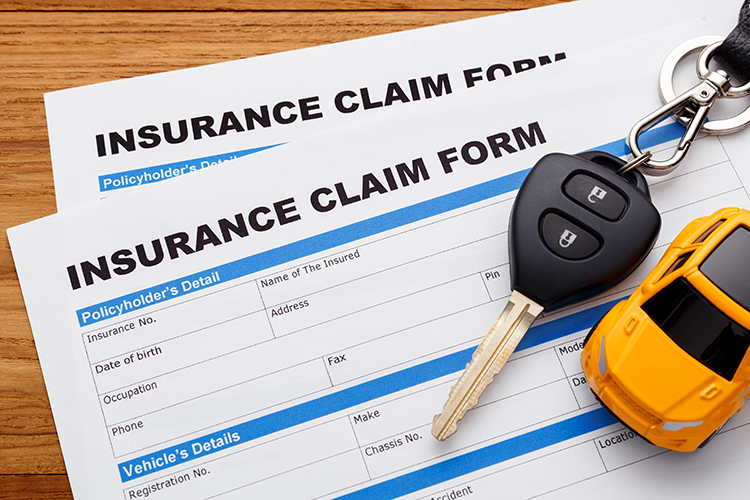 Car insurance claim form with car key on wood desk | Metro East, IL